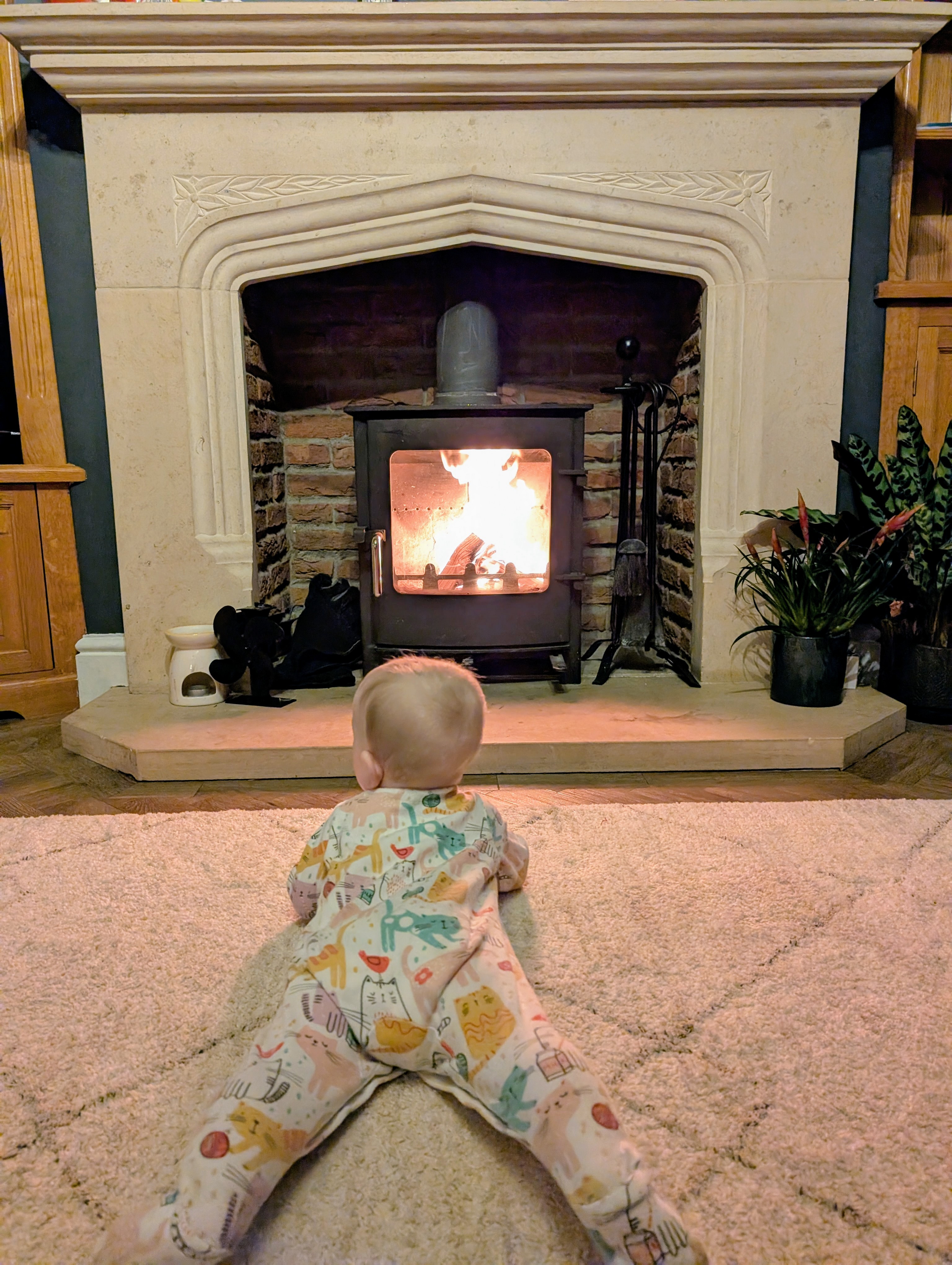 A baby in front of a fire in a living room