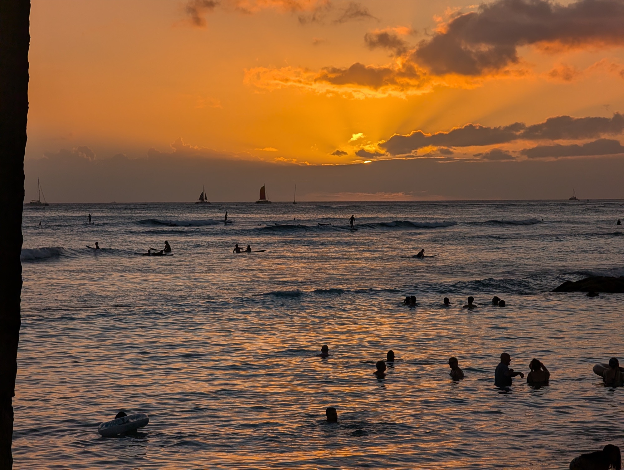 Swimmers and surfers silhouetted against an orange sunset over the
Pacific